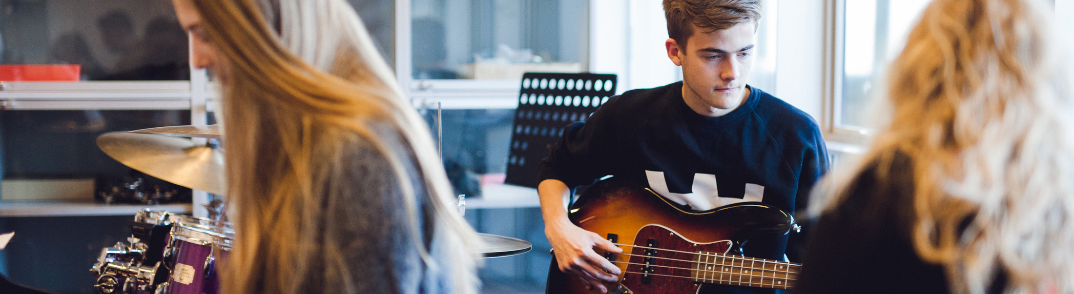 Drenge og piger sidder og spiller i musiklokalet.
