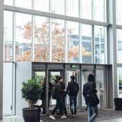Foto af indgangsdørene taget inde fra forhallen. Elever går ud af dørene.