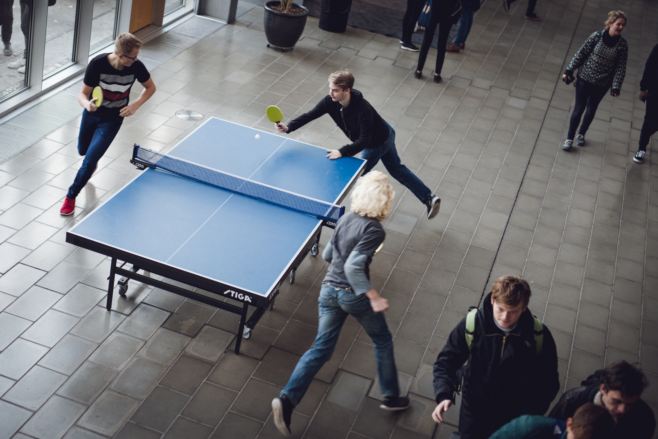 Foto af elever der løber rundt om bordtennisbord i forhallen og spiller bordtennis.