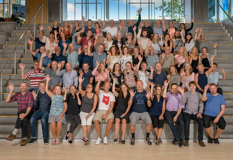 Foto af lærerkollegiet der sidder i aulaen og vinker velkommen. 2017