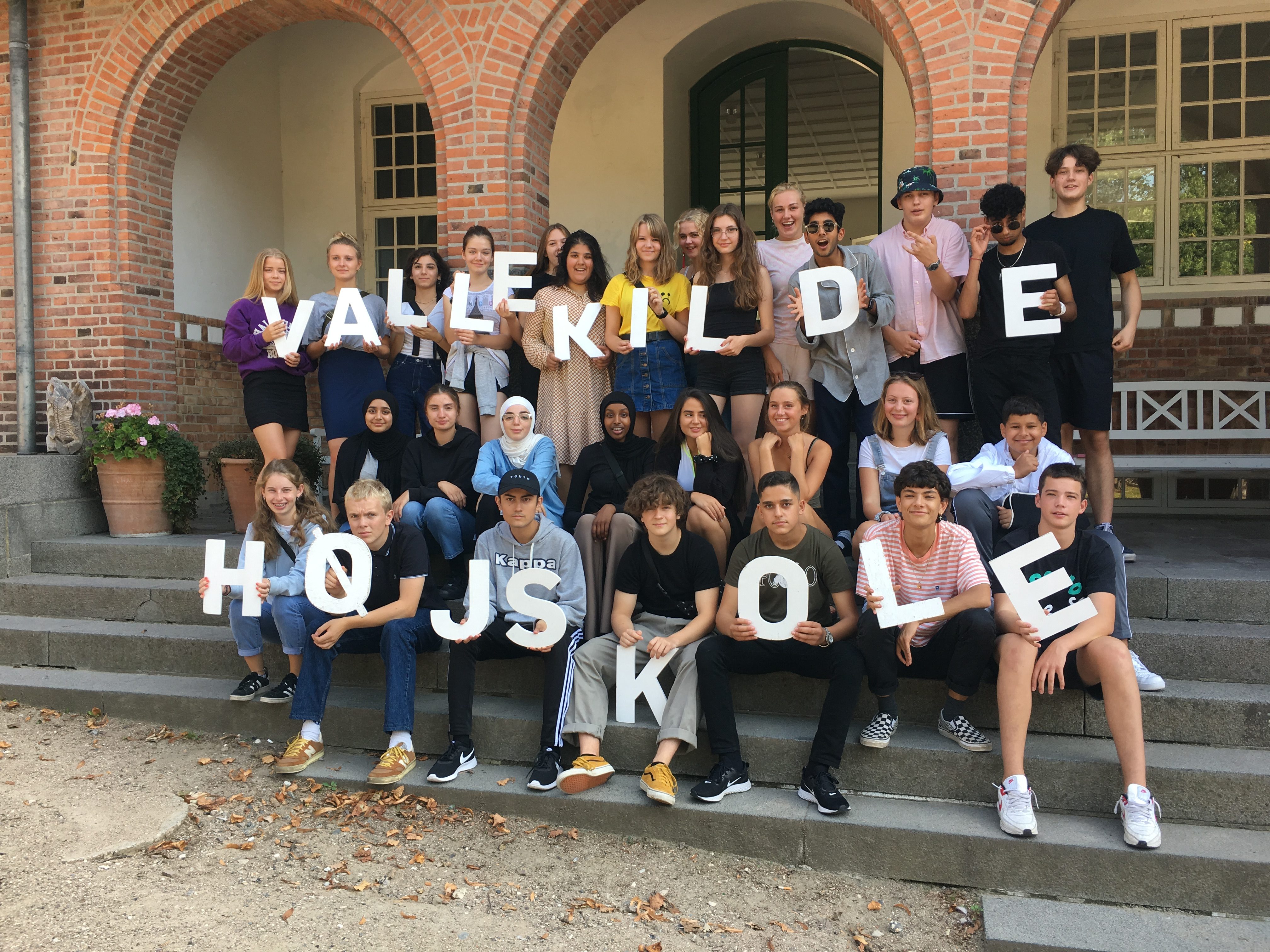 Foto af elever der sidder på trappen ved indgangen til Vallekilde Højskole